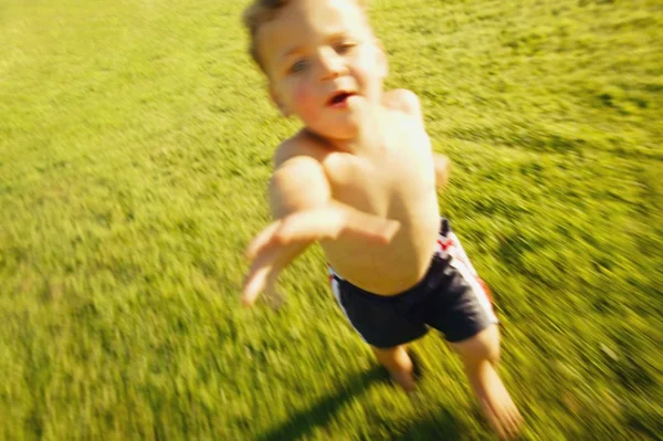 Мальчик, бегущий через грасс — стоковое фото