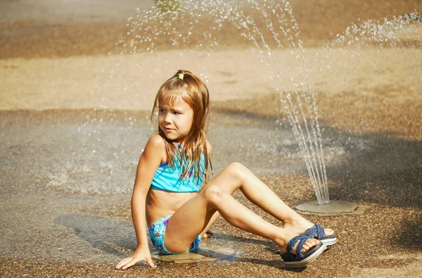 子供のスプリンクラーのそばに座って — ストック写真