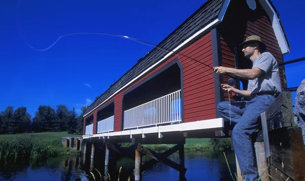 Hombre sentado en el puente de pesca —  Fotos de Stock