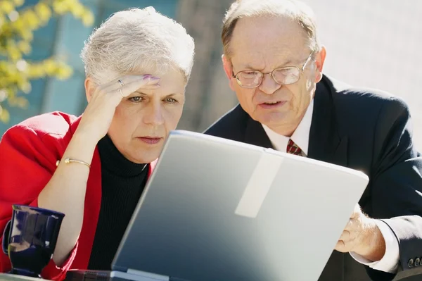 Twee mensen uit het bedrijfsleven op zoek naar een laptop — Stockfoto
