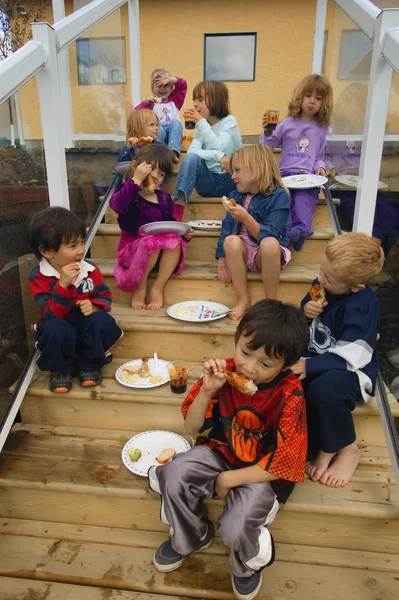 Children sit on the steps and eat food — Stock Photo, Image