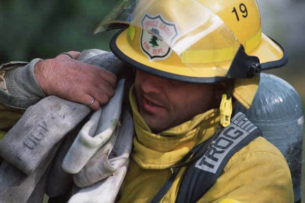 Feuerwehrmann trägt Schlauch — Stockfoto