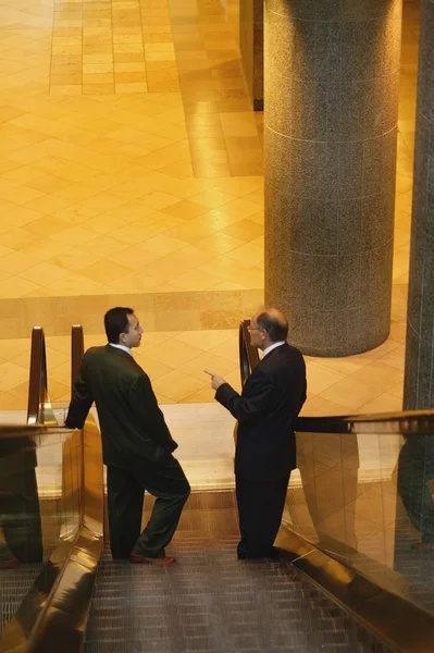 Dos hombres conversan sobre una escalera mecánica —  Fotos de Stock