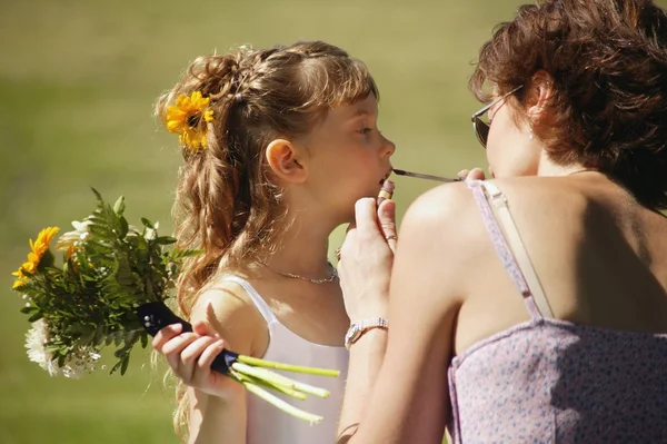 Blumenmädchen bekommt Lippenstift — Stockfoto
