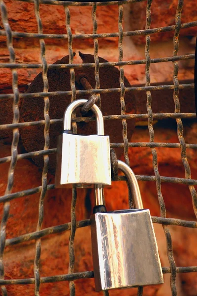 Vorhängeschlösser an einem verwitterten Maschendrahtzaun — Stockfoto