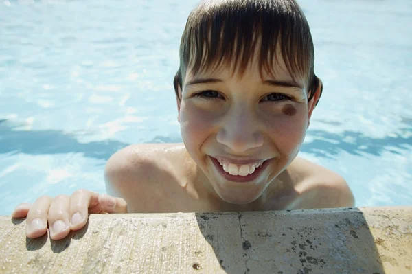 男孩爬上游泳池边 — 图库照片