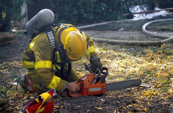 Пожарный начинает пилить бензопилой — стоковое фото