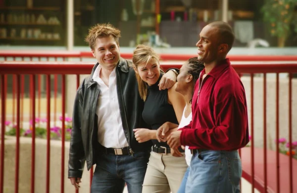 Dos parejas jóvenes caminando por la calle y sonriendo — Foto de Stock