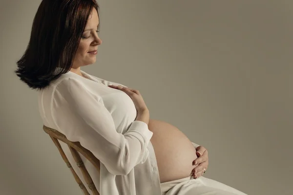 Eine Mutter blickt auf ihren schwangeren Bauch — Stockfoto