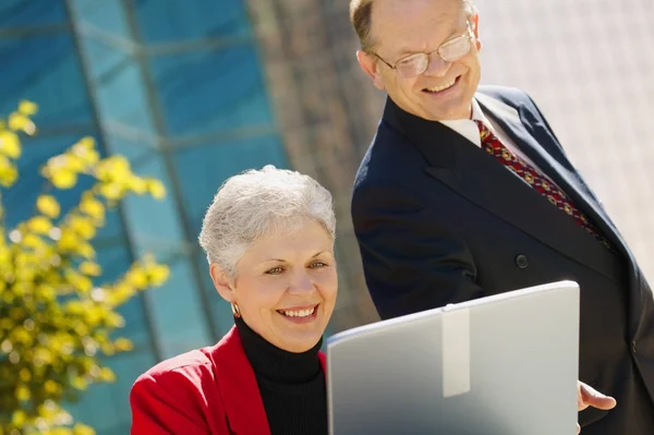 Twee mensen uit het bedrijfsleven op zoek naar een laptop — Stockfoto