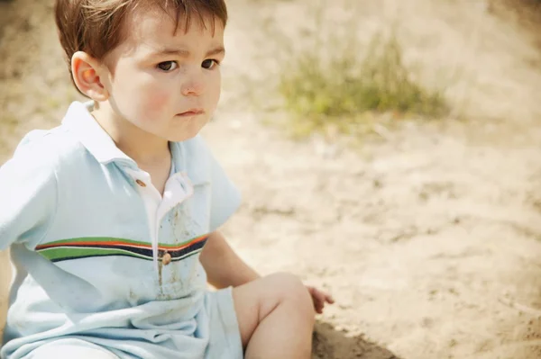 Kleine jongen zitten op het zand — Stockfoto