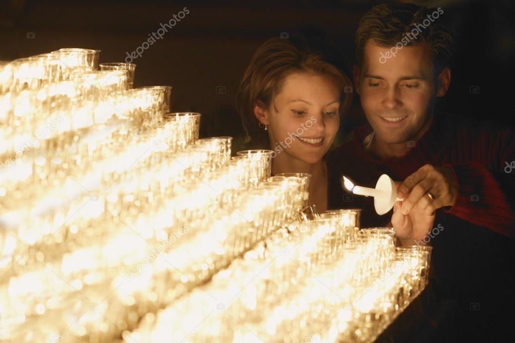 Young Couple Lighting A Candle