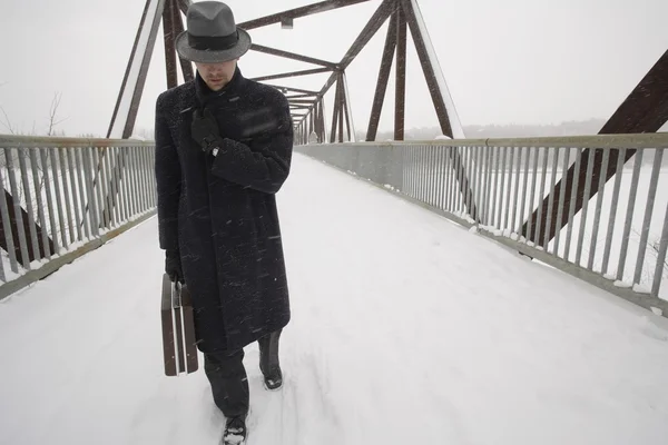 Podnikatel pěšky přes sníh krytý most — Stock fotografie