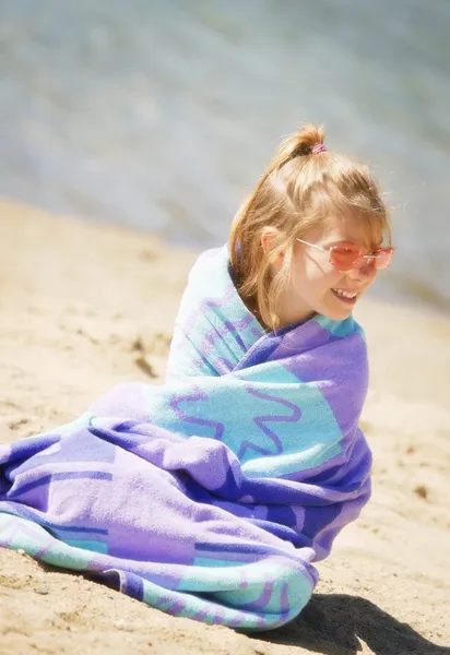 女孩坐在一条毛巾的沙滩上 — 图库照片