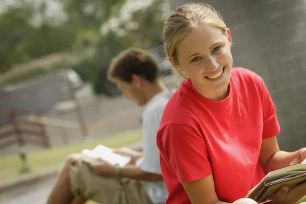 Sorridente studente lettura al di fuori — Foto Stock