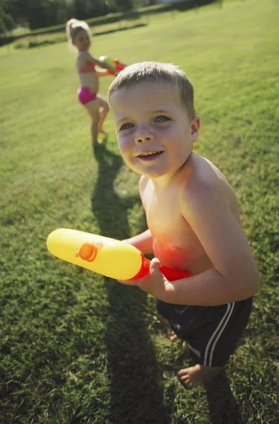 Kinder spielen im Park mit Wasserpistolen — Stockfoto