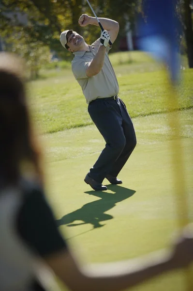 Kobieta trzyma flagę na putting green — Zdjęcie stockowe