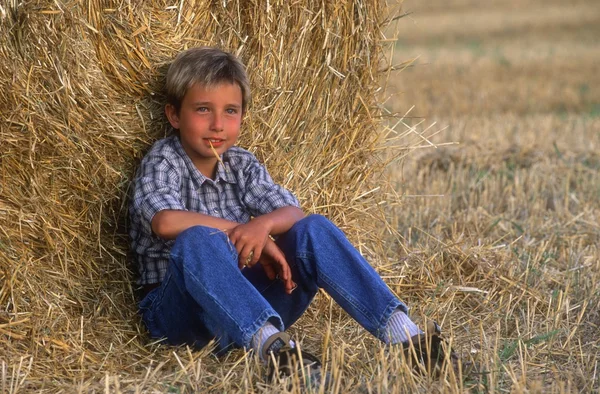 Jonge jongen zittend op baal hooi — Stockfoto