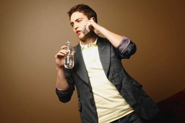 Человек с бутылкой воды и сотовым телефоном — стоковое фото