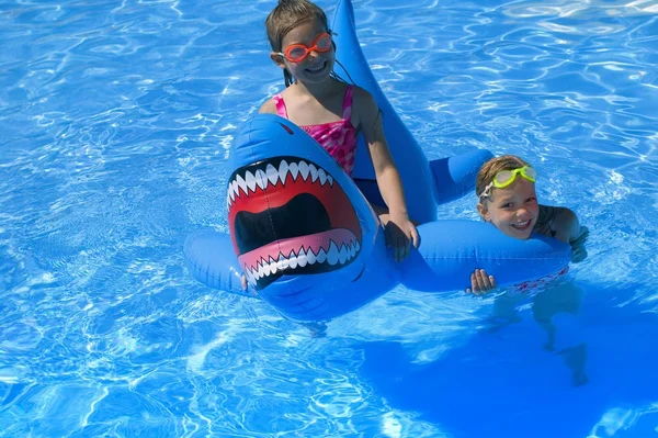 Flickor leker i poolen med uppblåsbar haj — Stockfoto