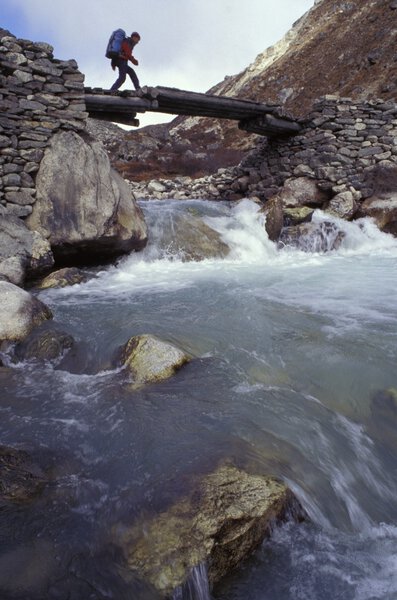 Man Crossing River On Wooden Bridge