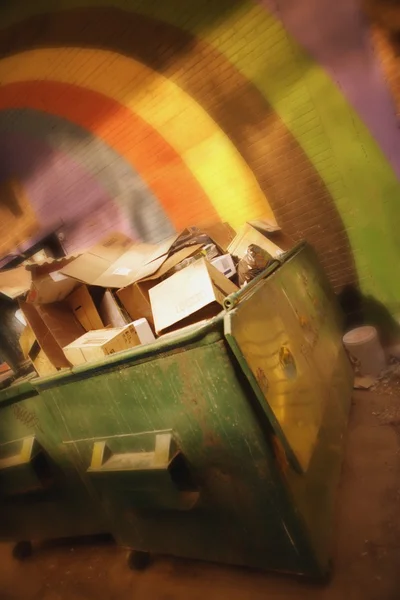 Картонные коробки в мусорном контейнере против цветной стены — стоковое фото