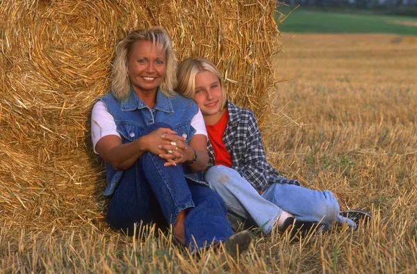 Moeder en dochter rusten in het hayfield — Stockfoto