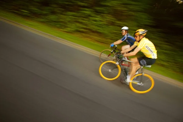 Two Cyclists Racing On Bikes