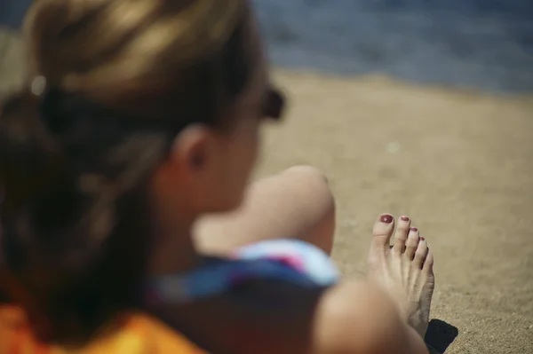 Mujer se sienta en una playa —  Fotos de Stock