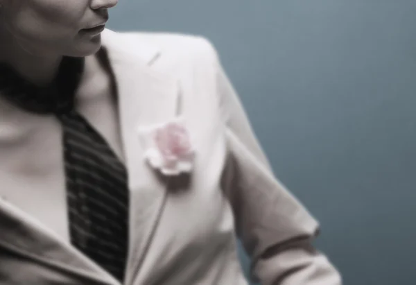 Kobieta w garniturze z różowy kwiat — Zdjęcie stockowe
