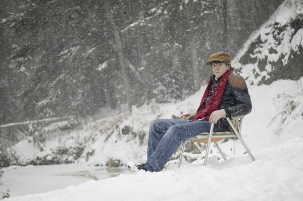 Человек, сидящий на стуле в снегу
