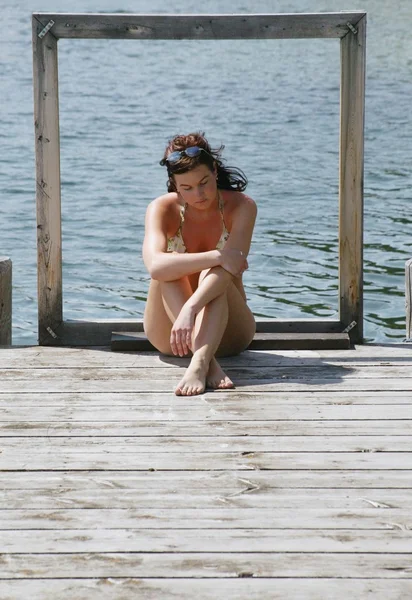 Donna si siede da solo su un dock — Foto Stock