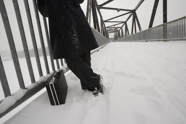 Uomo con valigetta in attesa sul ponte innevato — Foto Stock