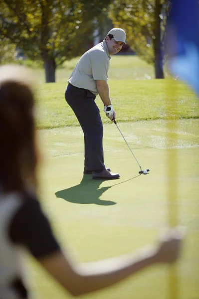 Kobieta trzyma flagę na putting green — Zdjęcie stockowe