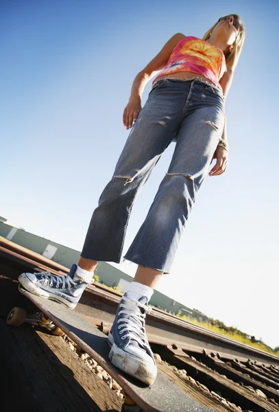 Vrouw op skate board op treinrails — Stockfoto