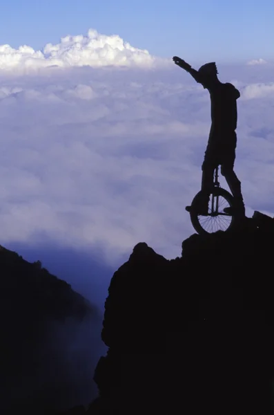 Adam tek tekerlekli sirk bisikletine binme cliff üzerinde — Stok fotoğraf