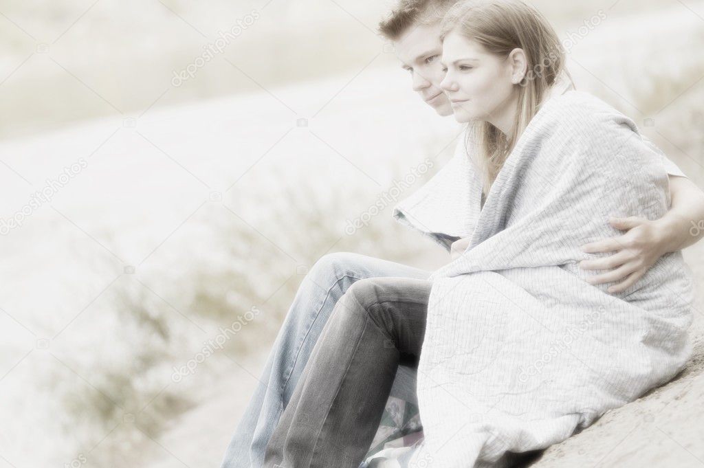 Couple Sitting On Beach With Blanket