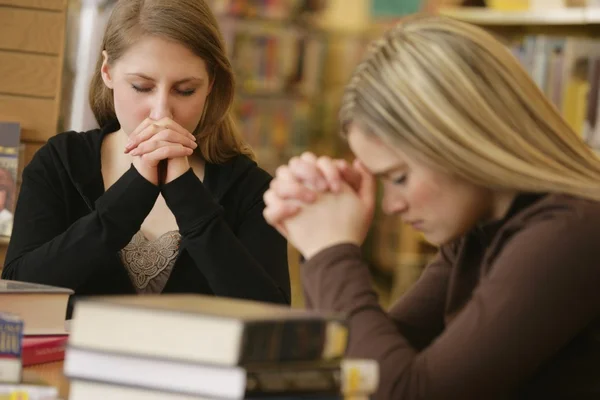 Две женщины молятся в библиотеке — стоковое фото