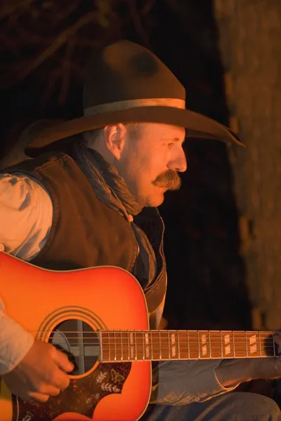 Vaquero tocando la guitarra por fogata — Foto de Stock