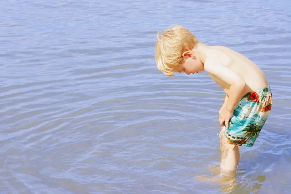 Een jonge jongen waden in water — Stockfoto