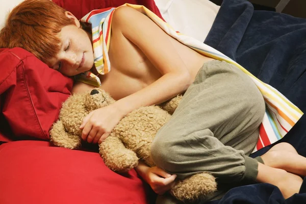 Junger Superheld schläft mit Teddybär — Stockfoto