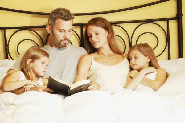 Familia en cama lectura de la Biblia —  Fotos de Stock