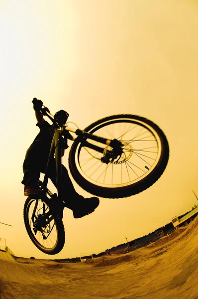 Silhouette di un ciclista contro un cielo giallo — Foto Stock