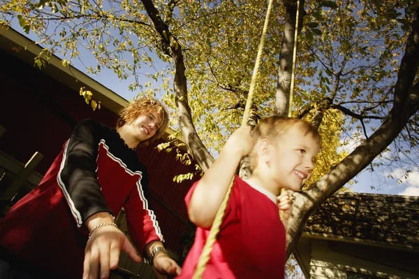 Trycka pojken på swing — Stockfoto