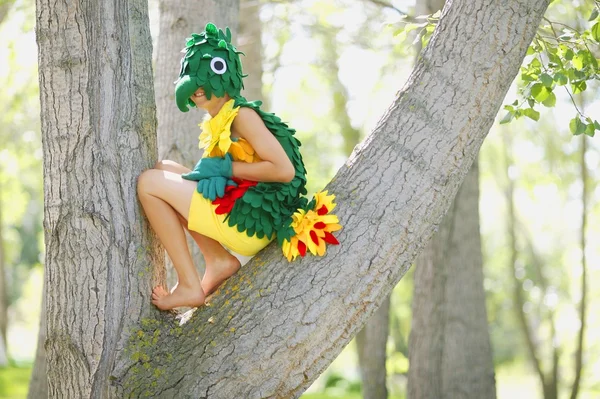 Un niño disfrazado de pájaro en un árbol —  Fotos de Stock