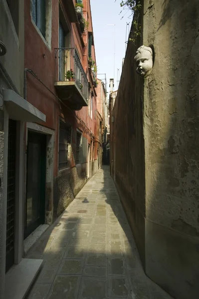 Estrecha calle peatonal con cara de querubín estatua en la pared de piedra — Foto de Stock