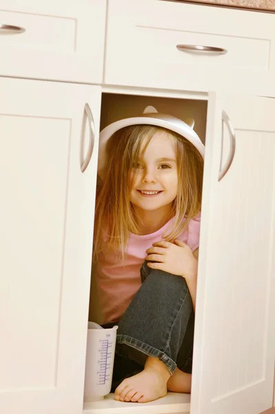 Kind verbergt in keuken kast — Stockfoto