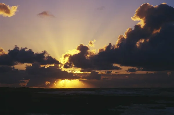 Wschód słońca przez ciemne chmury, piasek plaży park — Zdjęcie stockowe