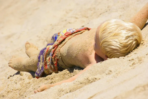 Criança coloca na areia — Fotografia de Stock