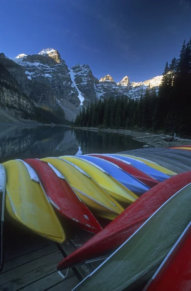 Fila de canoas volteadas y paisajes de montaña, Lago Moraine, Parque Nacional Banff, Alberta, Canadá — Foto de Stock